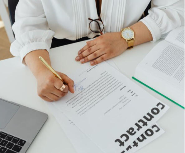 The image depicts a professional woman, manager or lawyer siging the contract